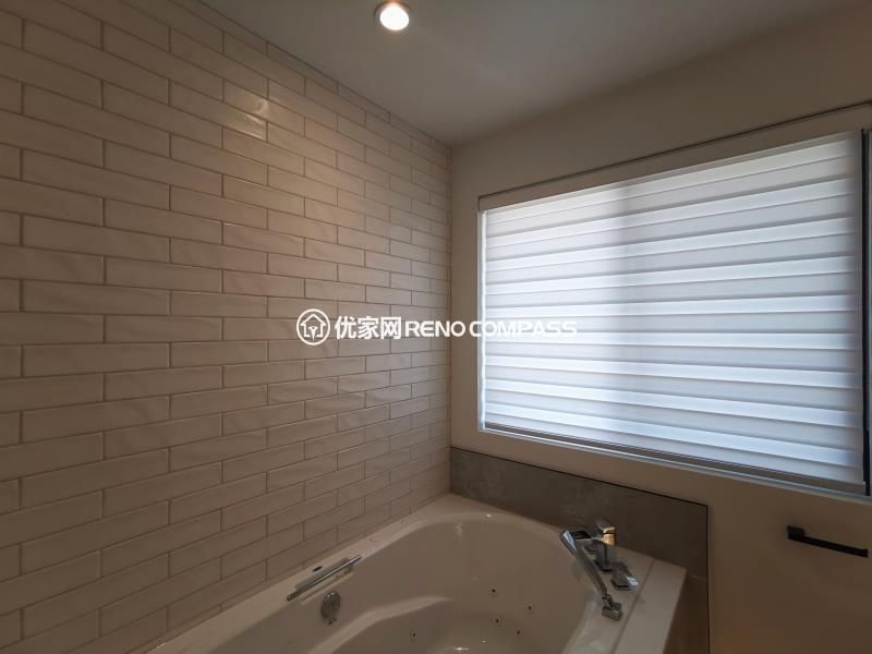 Bathtub area completed as part of a North York interior renovation, featuring a built-in soaking tub with a full-height tiled feature wall. Rectangular wall tiles create clean horizontal lines that visually extend the space, while the window introduces natural light and ventilation. Neutral tones and simple fixtures contribute to a calm, spa-inspired atmosphere designed for everyday comfort. This bathroom renovation was completed by a Toronto renovation company with a focus on material balance, layout efficiency, and long-term durability.
