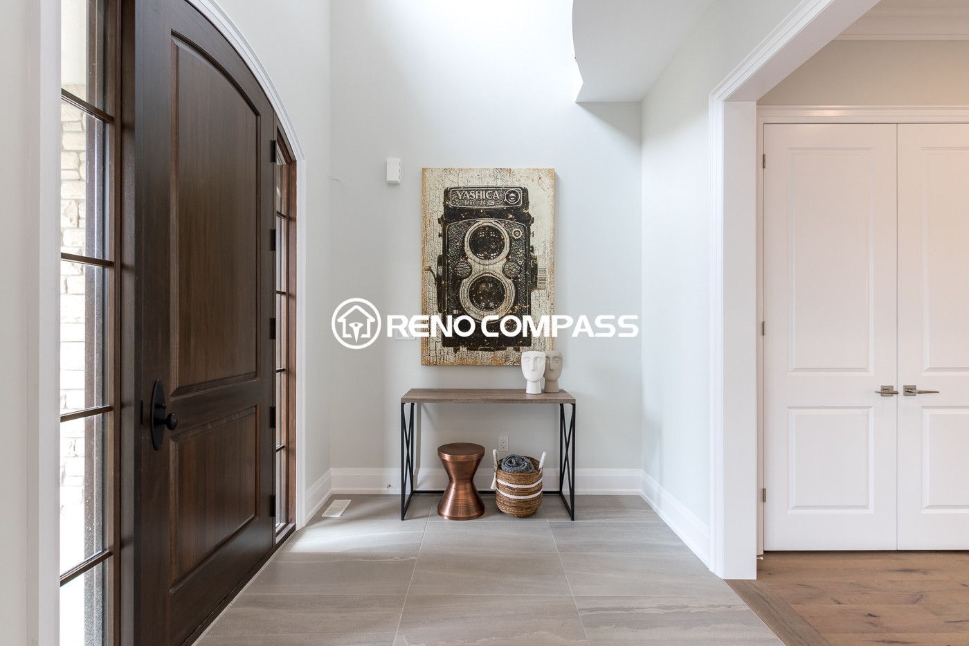 This image shows a bright and modern home entrance after a Newmarket flooring renovation project in Toronto. The homeowner selected engineered wood flooring, which provides the natural appearance and comfortable feel of solid hardwood while offering greater structural stability. Engineered wood floors are constructed with multiple layers of wood pressed together in a cross-grain structure, helping prevent expansion, cracking, and warping. This flooring upgrade enhances durability, improves moisture resistance, and creates a clean, elegant entry space for the home. Renovation completed by Reno Compass Inc., a Toronto renovation company specializing in flooring installation and interior upgrades.