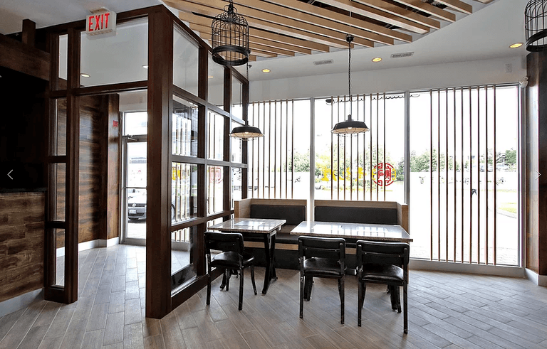 Modern restaurant renovation in Markham featuring window seating layout, custom wood ceiling design, decorative pendant lighting, and bright storefront dining area. Designed to enhance customer comfort, natural lighting, and dining experience in a commercial restaurant space. Completed by a trusted Toronto renovation company, Reno Compass Inc., specializing in restaurant and commercial renovation across the GTA.