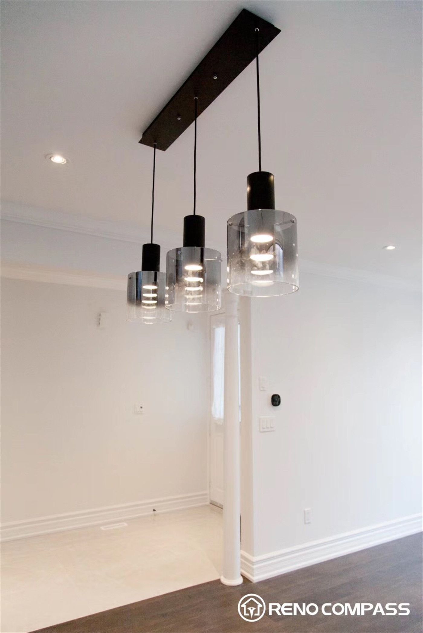 This Markham interior renovation features an open concept layout connecting the living and dining areas with seamless hardwood flooring. The space is enhanced by modern pendant lighting, large windows for natural light, and a stylish staircase with iron railings, creating a clean, spacious, and contemporary home environment.