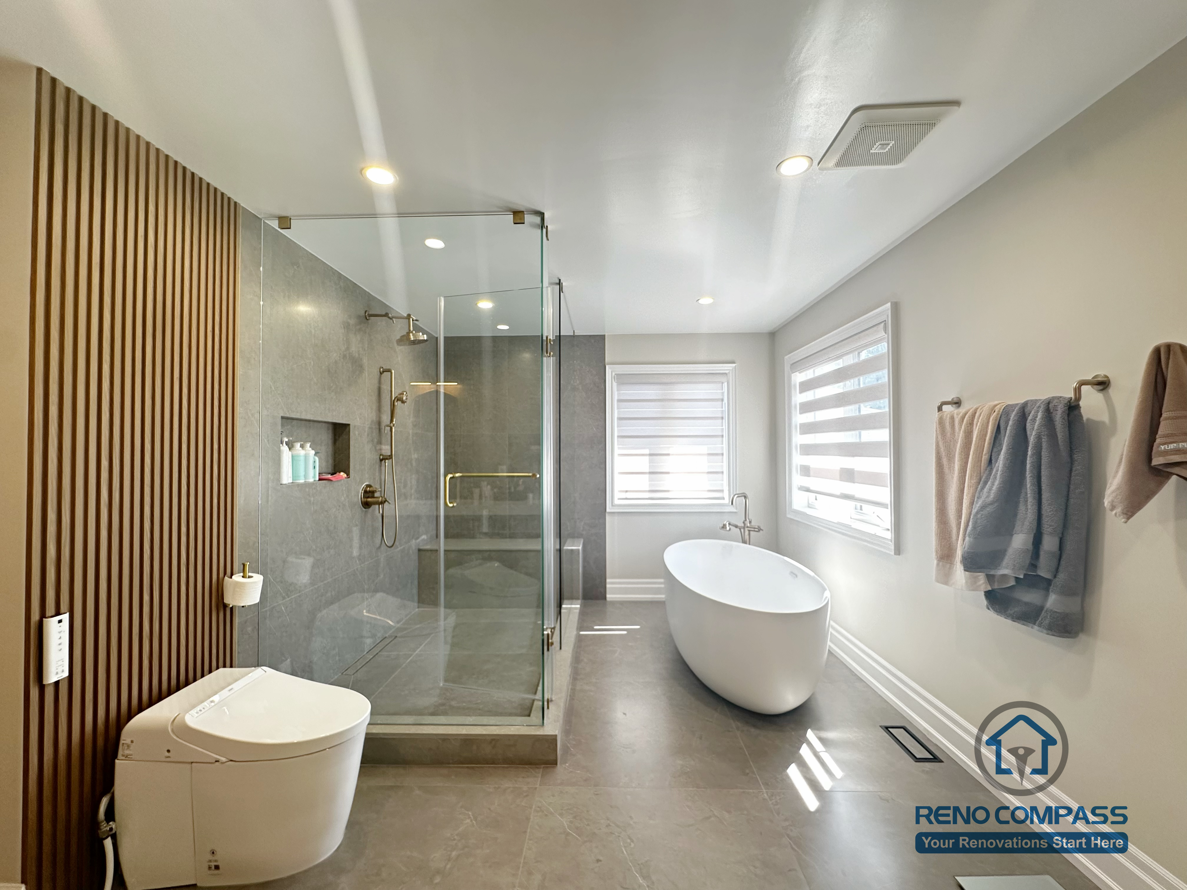 This bathroom renovation in North York combines a frameless glass shower enclosure with a freestanding tub and soft natural light. The spacious layout and refined material selection create a luxury spa-like experience.