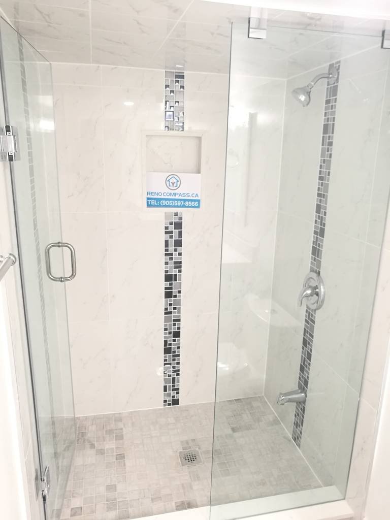 Bathroom renovation project in Pickering featuring a frameless glass shower enclosure, built-in wall niche, mosaic tile accent strip, and modern chrome fixtures. The clean tile layout and clear glass design create a bright, open shower space, showcasing professional workmanship by a Toronto renovation company.