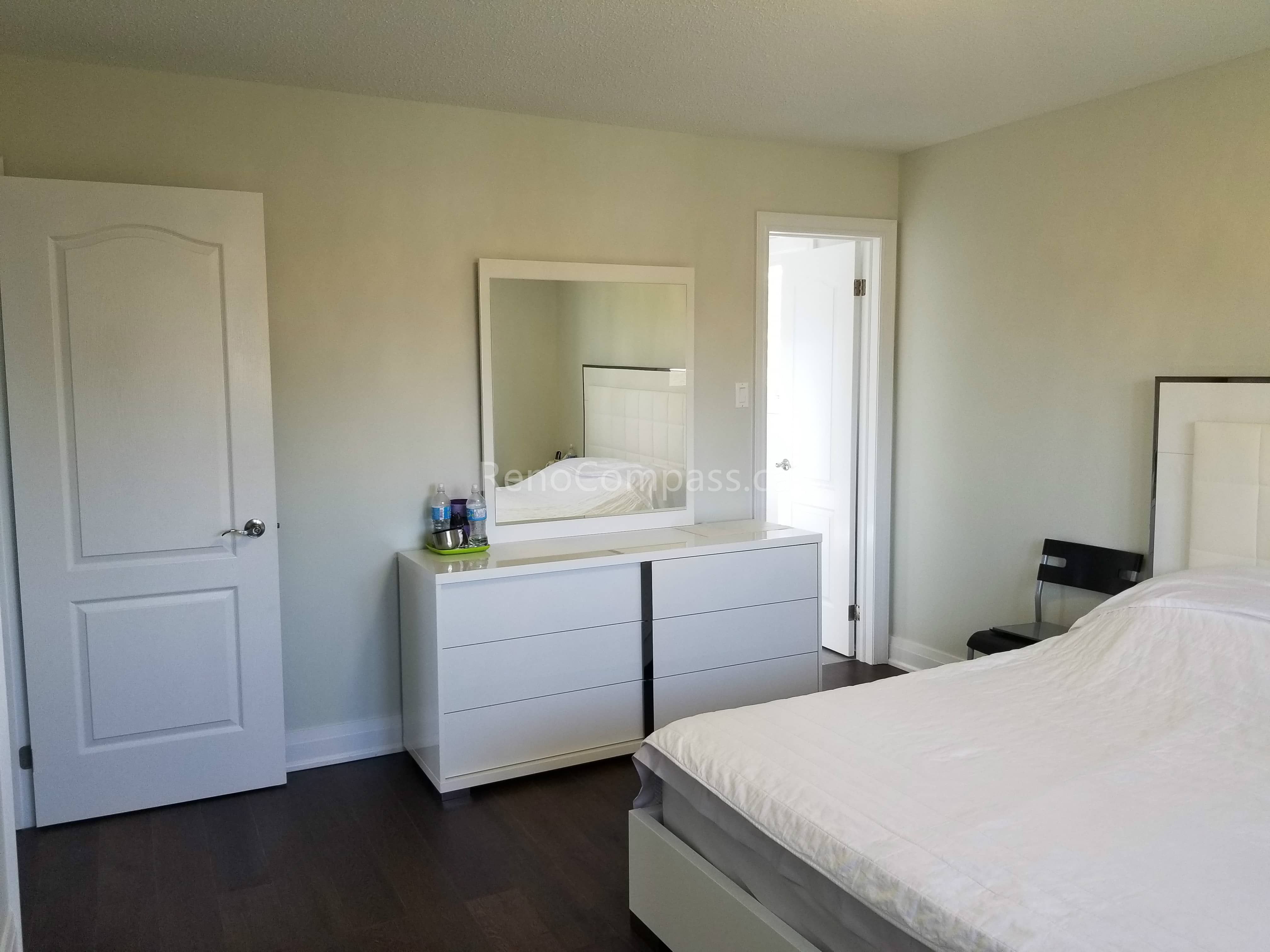 This Toronto interior renovation features a clean and modern bedroom upgrade with dark hardwood flooring, fresh neutral wall paint, and elegant white furniture. The refreshed layout enhances comfort, brightness, and functionality, creating a peaceful living space. Completed by a trusted Toronto renovation contractor, this project reflects Reno Compass Inc.’s attention to detail and expertise in full home interior renovation and finishing.