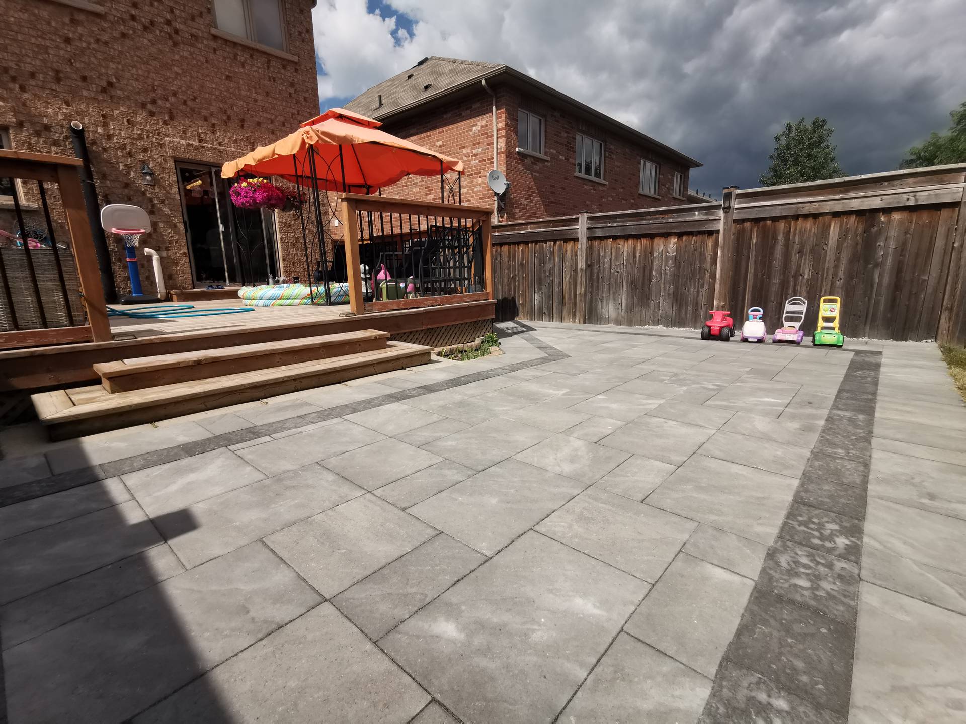 This Aurora backyard interlocking project features a spacious paver patio seamlessly connected to a raised wooden deck. Large-format concrete pavers provide a durable, level surface ideal for outdoor activities, family gatherings, and everyday use. The clean layout enhances drainage and long-term performance while maintaining a modern and low-maintenance finish. The interlocking patio creates a functional and inviting outdoor living space, perfectly suited for residential backyards in Aurora.