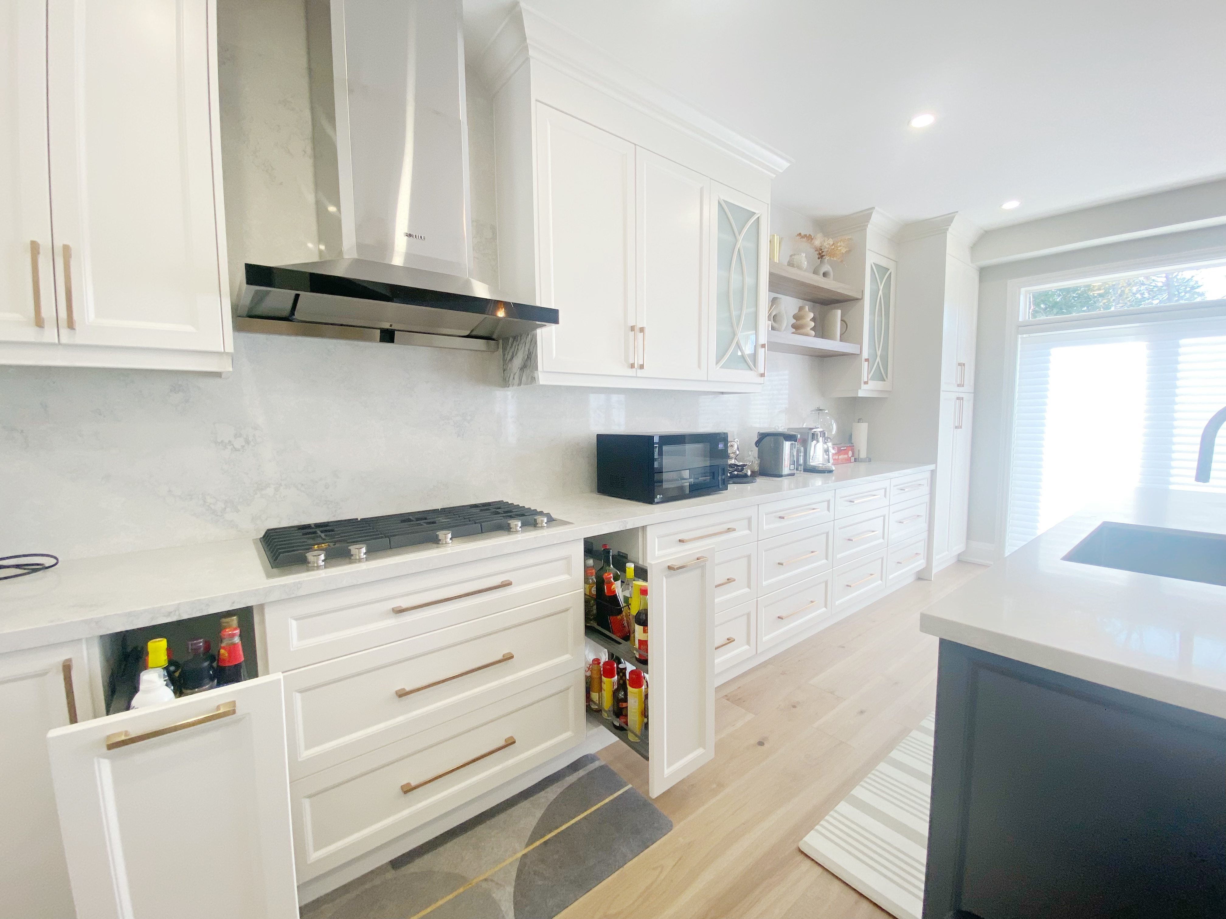 A detailed view of custom kitchen cabinetry completed as part of a Richmond Hill interior renovation. This kitchen renovation showcases full-height cabinets, integrated pull-out storage, quartz backsplash, stainless steel range hood, and efficient cooking-zone organization.