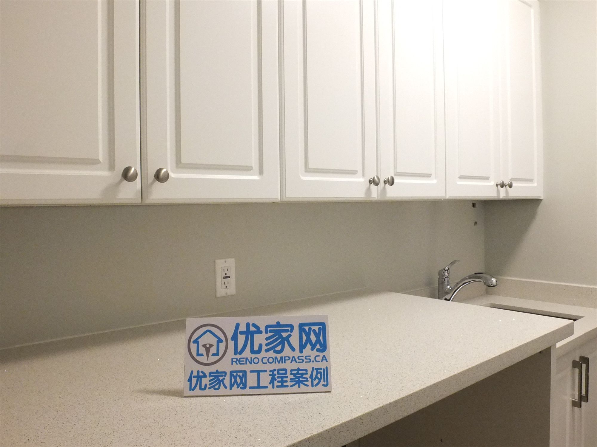 This Richmond Hill basement renovation highlights a detailed view of the utility area, featuring a quartz countertop, custom upper cabinets, and a built-in sink. The clean finishes and practical layout provide efficient storage and workspace, ideal for laundry or additional household use.