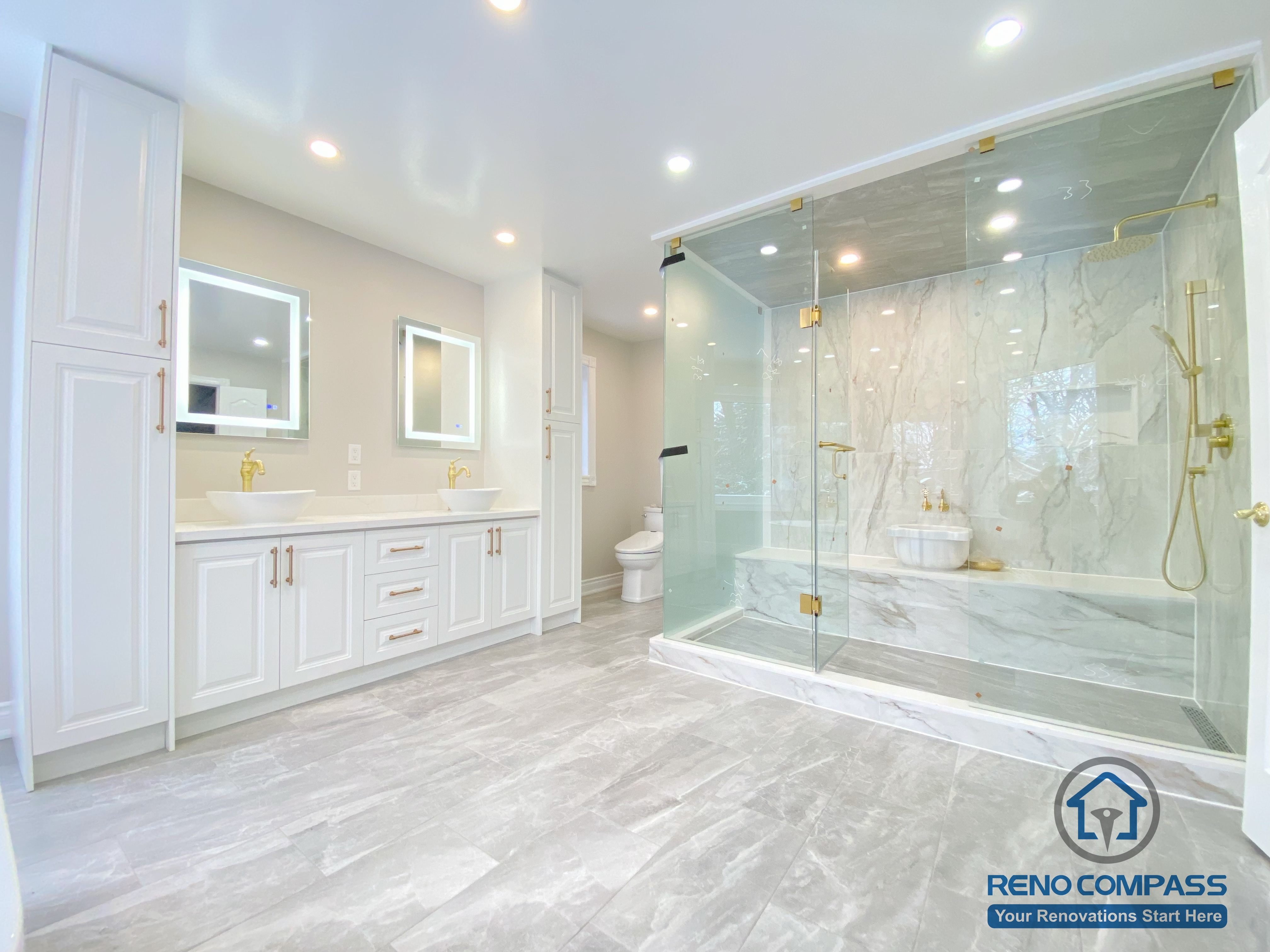 This Richmond Hill bathroom renovation showcases a bright and elegant design featuring a frameless glass shower enclosure, built-in bathtub, marble-style wall tiles, and gold-finish fixtures. The custom white vanity with integrated lighting mirror and large-format floor tiles enhance both functionality and visual openness. This project reflects high-quality craftsmanship and thoughtful layout planning for a modern bathroom renovation in Richmond Hill.