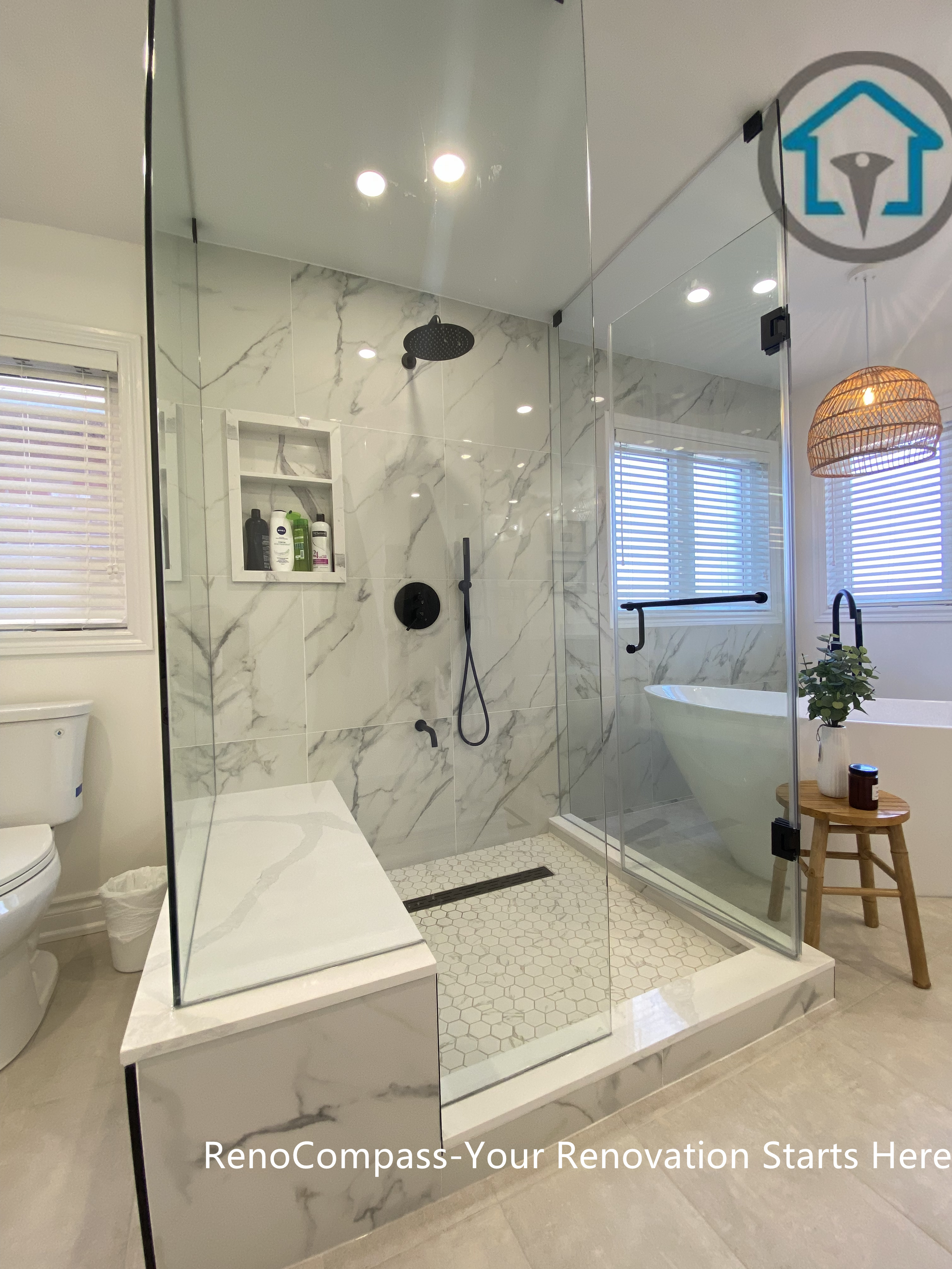 Contemporary Oakville bathroom renovation showcasing a frameless glass walk-in shower, marble-look wall tiles, matte black rain shower system, and hexagon mosaic shower floor. This bathroom remodel highlights precise detailing, clean drainage design, and a modern spa-style layout completed by an experienced Toronto renovation company.