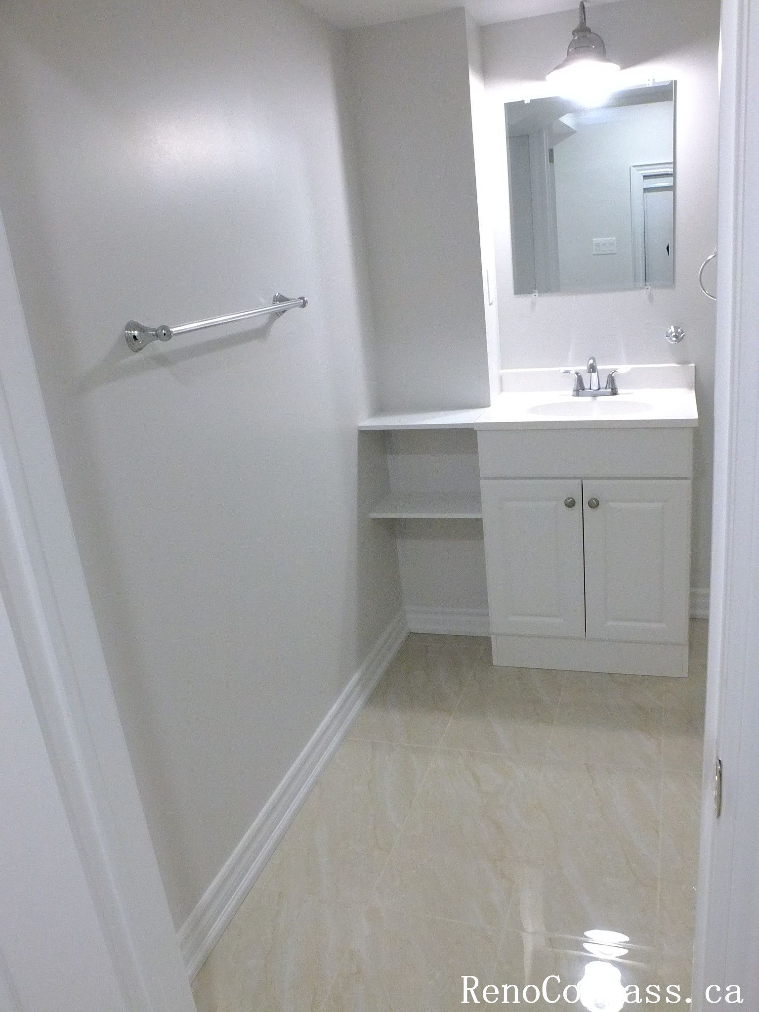 Bright and modern basement bathroom renovation in Richmond Hill with sleek white tiles, glass shower enclosure, and efficient layout by RenoCompass.ca.