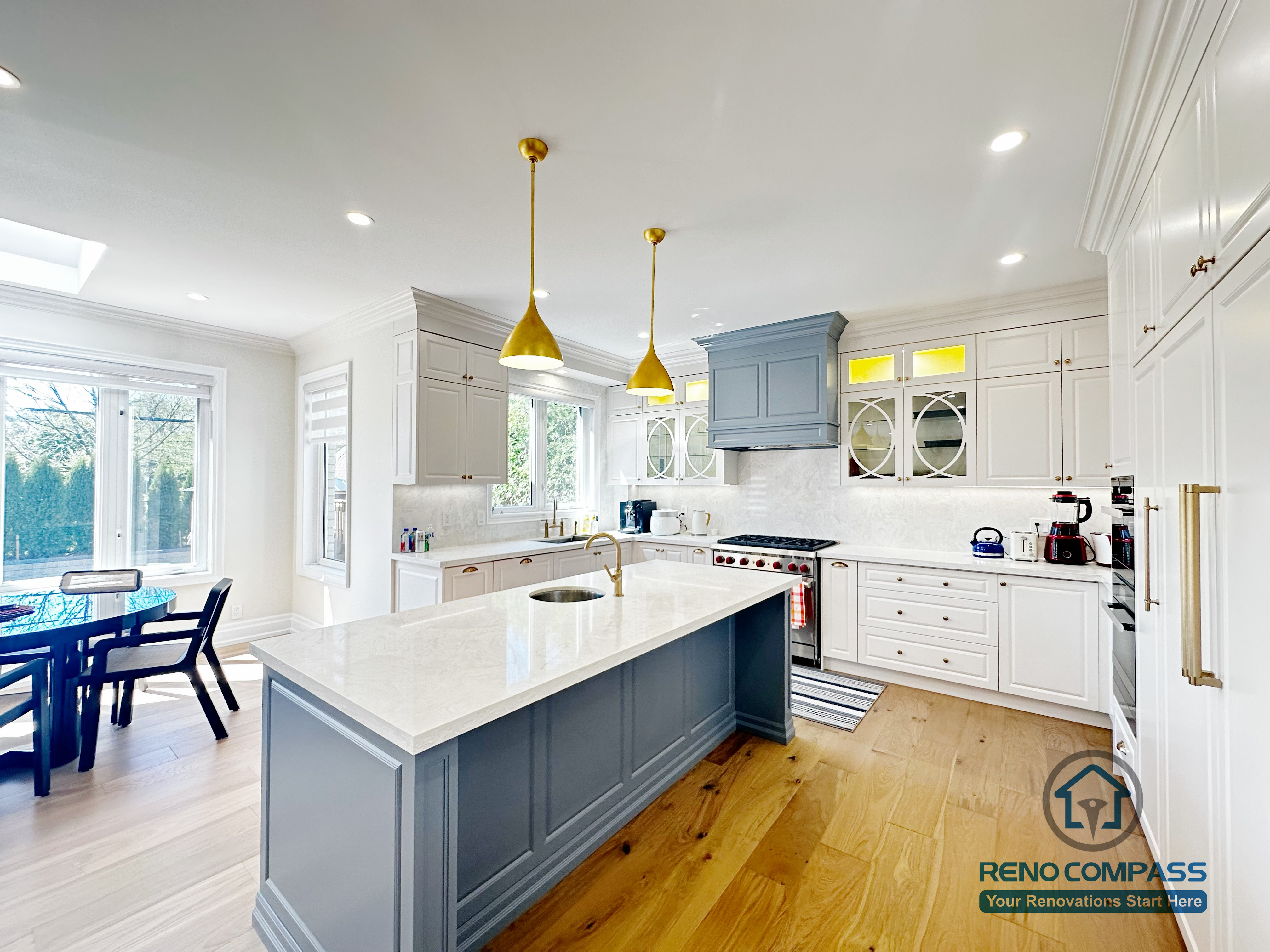 This North York kitchen renovation features a spacious central island with quartz countertops, custom cabinetry in a soft blue and white palette, and integrated pendant lighting. The open-concept layout enhances natural light and flow between the kitchen and dining area, creating a functional and elegant space designed for everyday living and entertaining. Completed by Reno Compass with a focus on craftsmanship, proportion, and long-term usability.