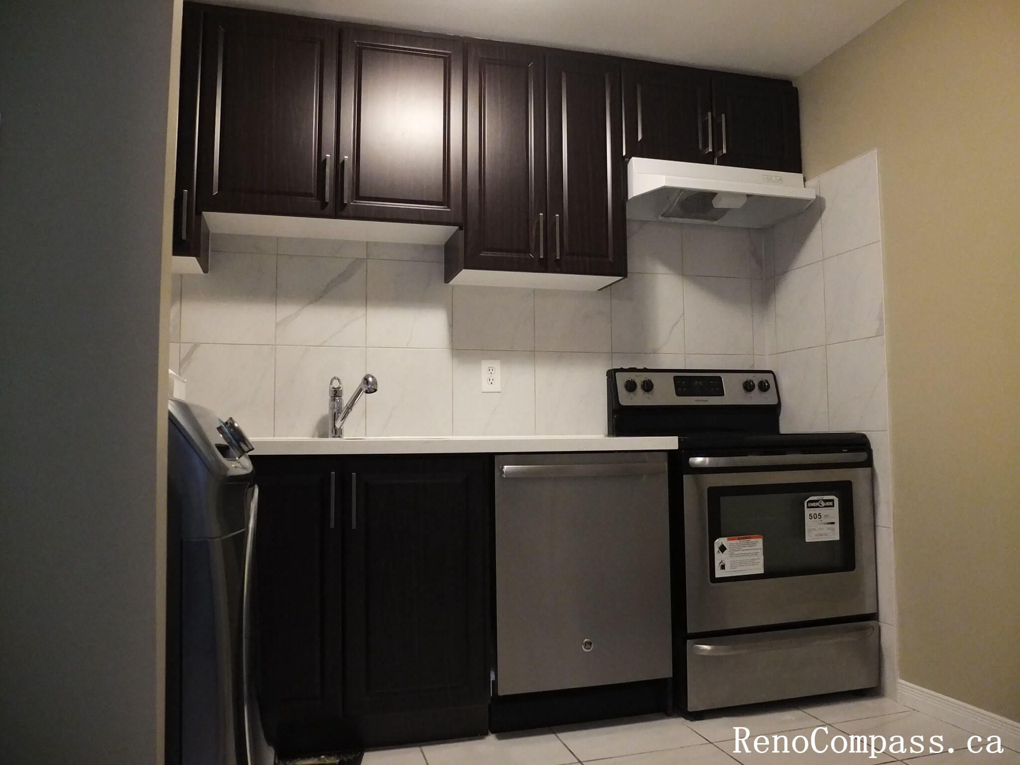 A sleek kitchen transformation in Mississauga featuring custom espresso-colored cabinetry, stainless steel appliances, and a clean white tile backsplash. Professional kitchen remodeling services by Reno Compass.