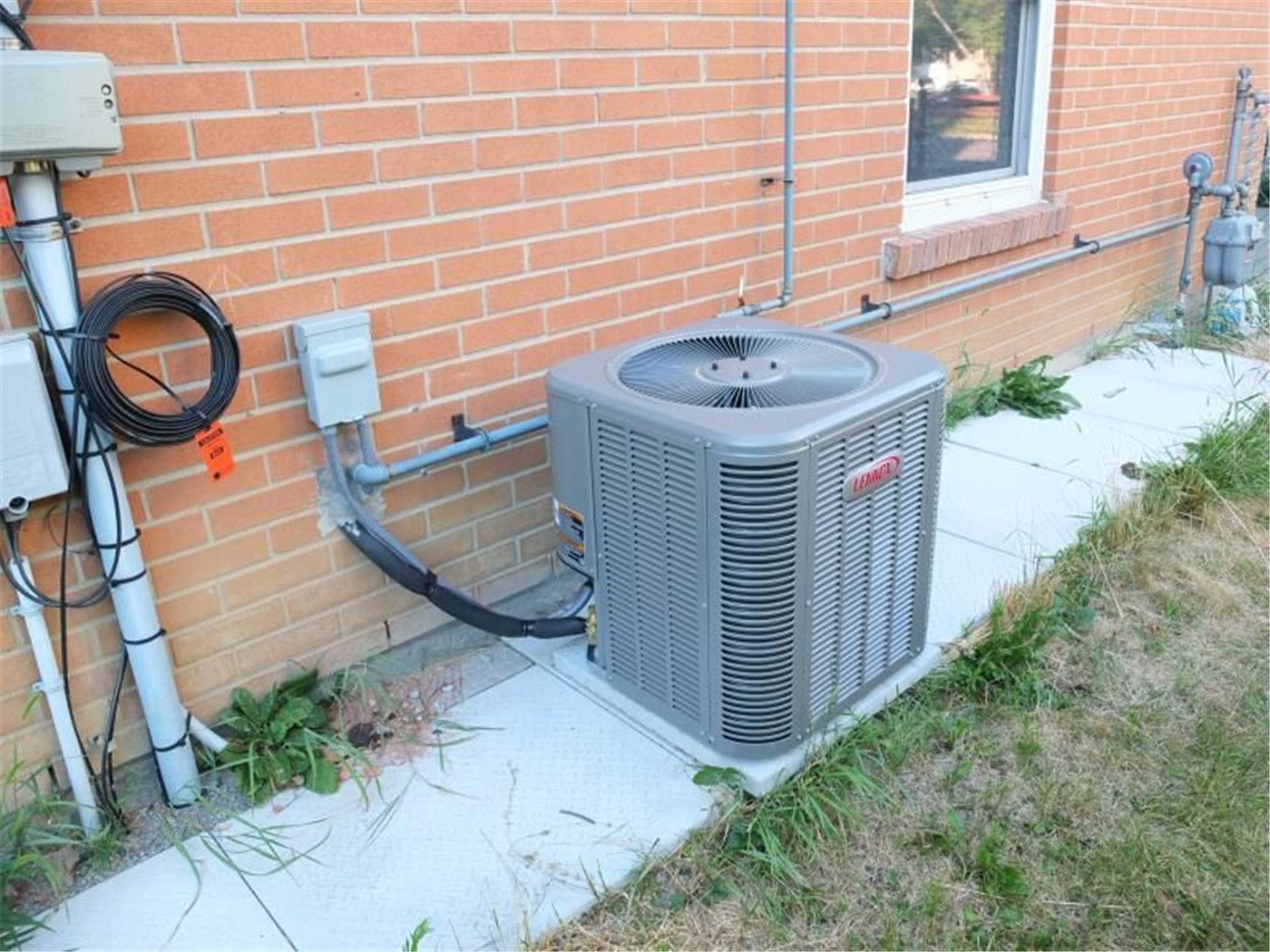 Professional outdoor air conditioner condenser installation by Reno Compass in Toronto. This energy-efficient HVAC unit is securely mounted on a raised stand with proper drainage and ventilation clearance, ensuring optimal cooling performance, durability, and safe operation for residential homes. Installed by licensed technicians for long-term reliability and comfort.