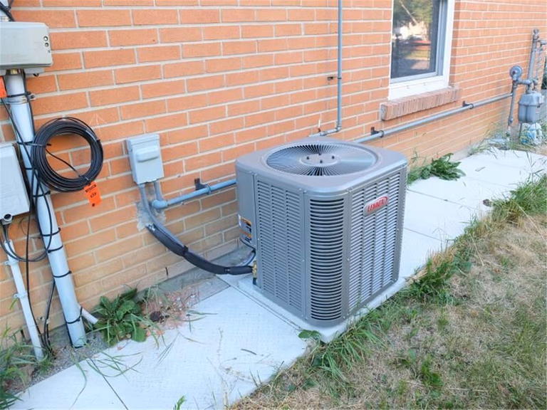 Professional outdoor air conditioner condenser installation by Reno Compass in Toronto. This energy-efficient HVAC unit is securely mounted on a raised stand with proper drainage and ventilation clearance, ensuring optimal cooling performance, durability, and safe operation for residential homes. Installed by licensed technicians for long-term reliability and comfort.
