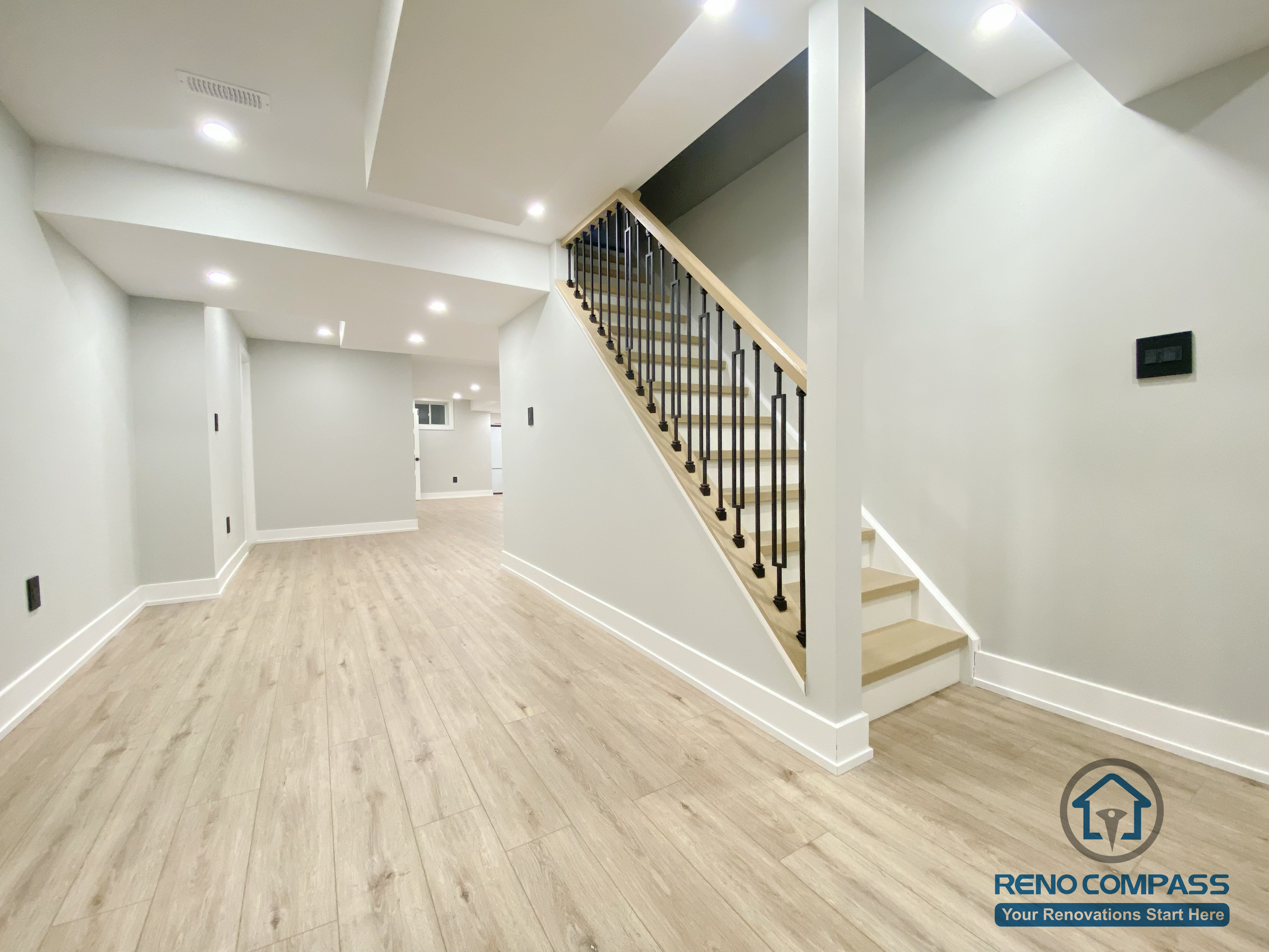This Aurora basement renovation features a well-integrated staircase and open hallway layout designed to improve flow, safety, and accessibility between levels. The space includes wood-look flooring, black metal stair railings, soft neutral wall finishes, and recessed ceiling lighting that enhances brightness throughout the lower level. Completed by a Toronto renovation company, this basement renovation highlights clean structural planning and functional circulation within a modern basement design.