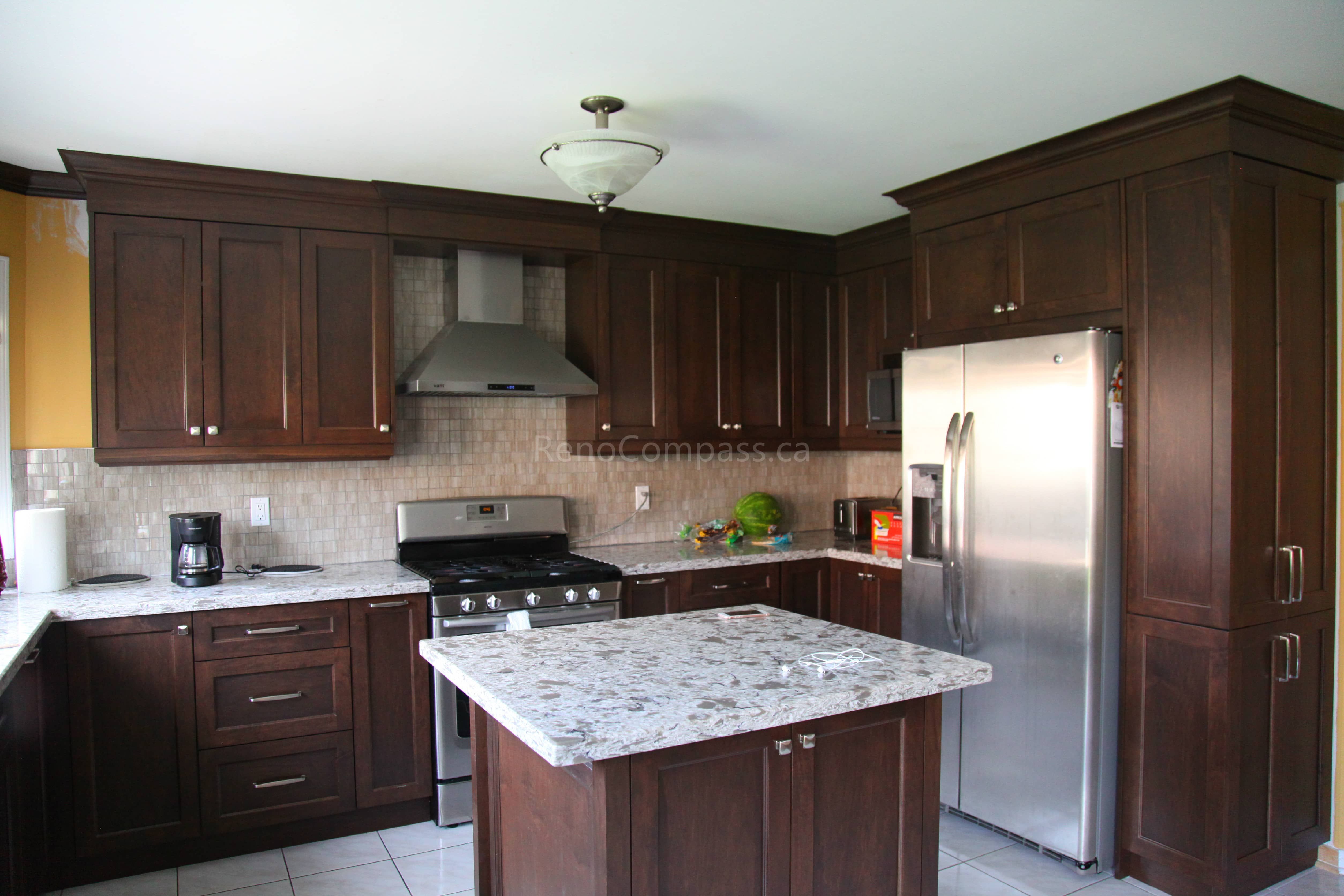 This Markham kitchen renovation features rich dark wood cabinetry, a custom quartz island, and modern stainless steel appliances, creating a warm and functional cooking space. Designed and completed by a professional Toronto renovation company, the layout enhances storage, workflow, and overall visual appeal while maintaining a timeless and elegant kitchen design.