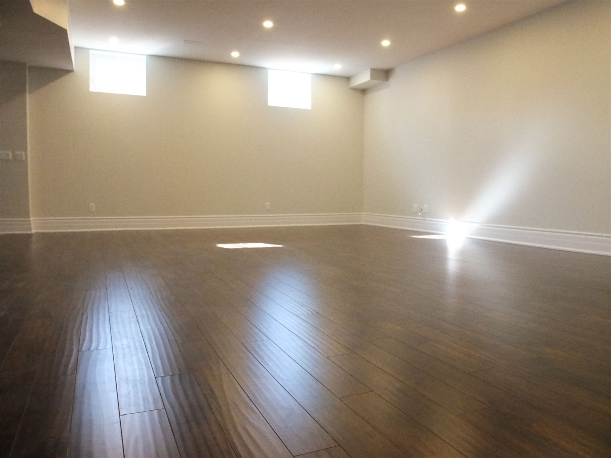 This Richmond Hill basement renovation features a bright and spacious open area designed for flexible living and entertainment. The space is finished with premium dark hardwood flooring, modern recessed pot lights, and neutral wall tones that enhance natural light from basement windows. A clean and open layout creates a comfortable environment ideal for a recreation room, home gym, or additional family living space, professionally renovated to improve functionality and home value.