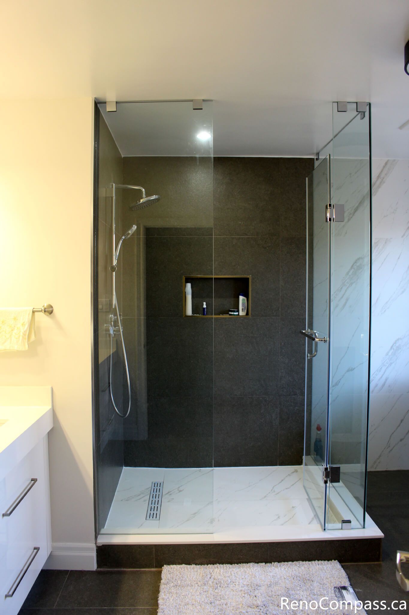 This Mississauga bathroom renovation features a walk-in glass shower with a built-in wall niche, large-format wall tiles, and a linear floor drain. The frameless enclosure and clean tile layout create a modern, functional shower space designed for comfort, durability, and easy maintenance.