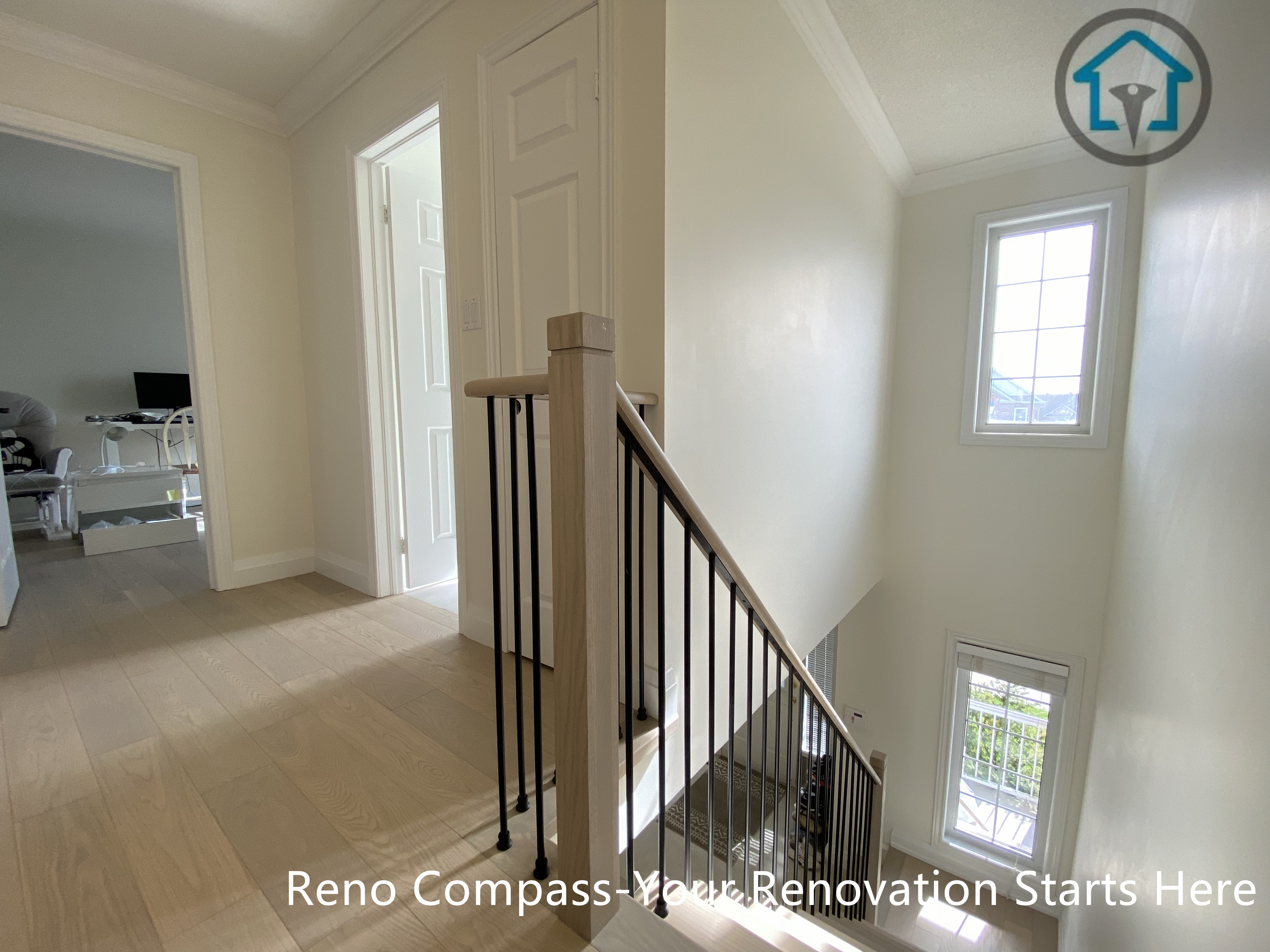 Upper hallway and staircase renovation in Markham showcasing light oak hardwood flooring, square wood newel posts, and black iron balusters. The vertical window design brings in natural light, enhancing the brightness and openness of the stairwell. This flooring and staircase upgrade was completed by a professional Toronto renovation company with attention to safety, clean lines, and long-term durability.