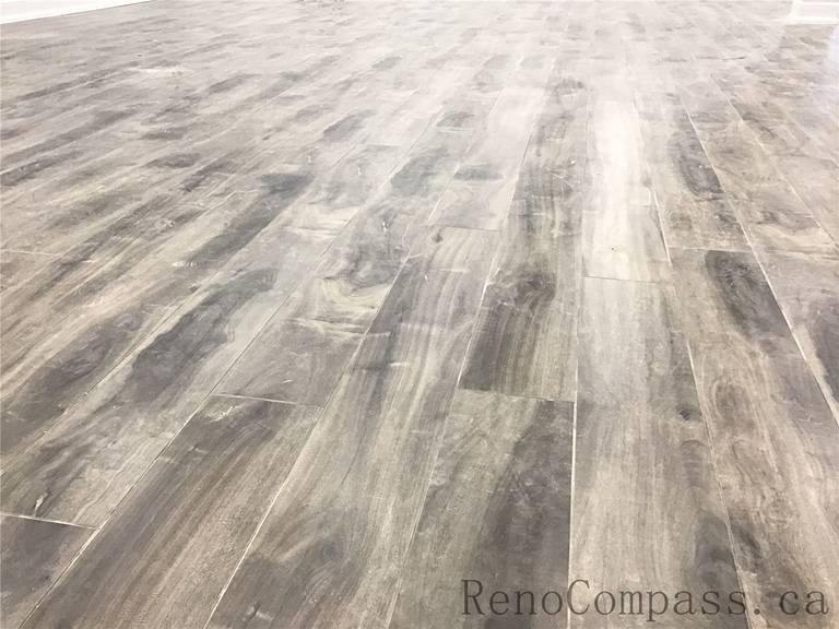 Close-up of premium wood-look vinyl plank flooring installed in a Richmond Hill basement renovation. This durable, waterproof flooring solution offers a modern grey-brown tone with natural texture, making it ideal for high-traffic basement living spaces. Professionally installed as part of a high-quality basement renovation by a trusted Toronto Renovation Company.