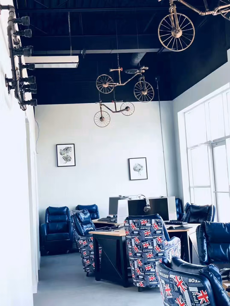 Interior space from a North York commercial renovation project featuring a modern gaming lounge layout. The design includes computer stations, comfortable seating, large windows for natural light, and unique bicycle-themed ceiling decorations that create a stylish and engaging entertainment environment.