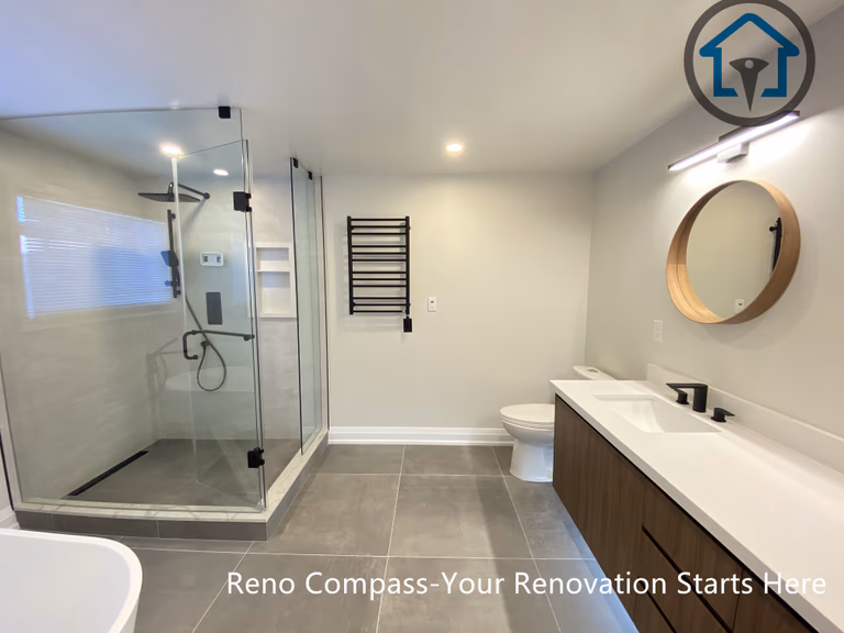 Contemporary bathroom renovation in Markham showcasing a custom double sink vanity, integrated LED mirror lighting, matte black faucets, and large-format floor tiles. The design balances clean lines, warm wood tones, and practical storage, completed by a trusted Toronto renovation company.