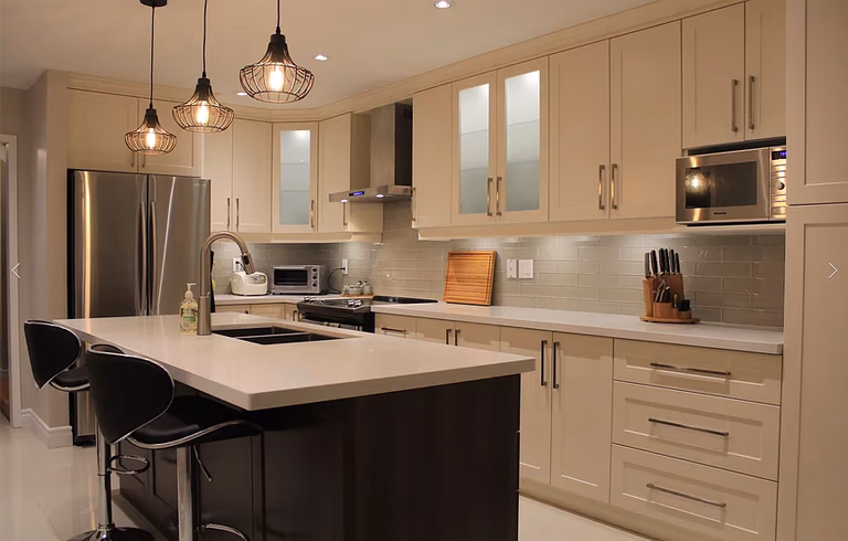 This Mississauga kitchen renovation features custom cream cabinetry, a large quartz island, modern pendant lighting, and upgraded backsplash design. Completed by a professional Toronto renovation company, the project focuses on improving functionality, storage, and modern aesthetics. The spacious island with built-in sink and seating enhances daily use and entertaining, while new lighting and finishes create a warm, elegant atmosphere. Ideal for homeowners in Mississauga seeking a stylish and practical kitchen upgrade with high-quality craftsmanship and thoughtful layout planning.