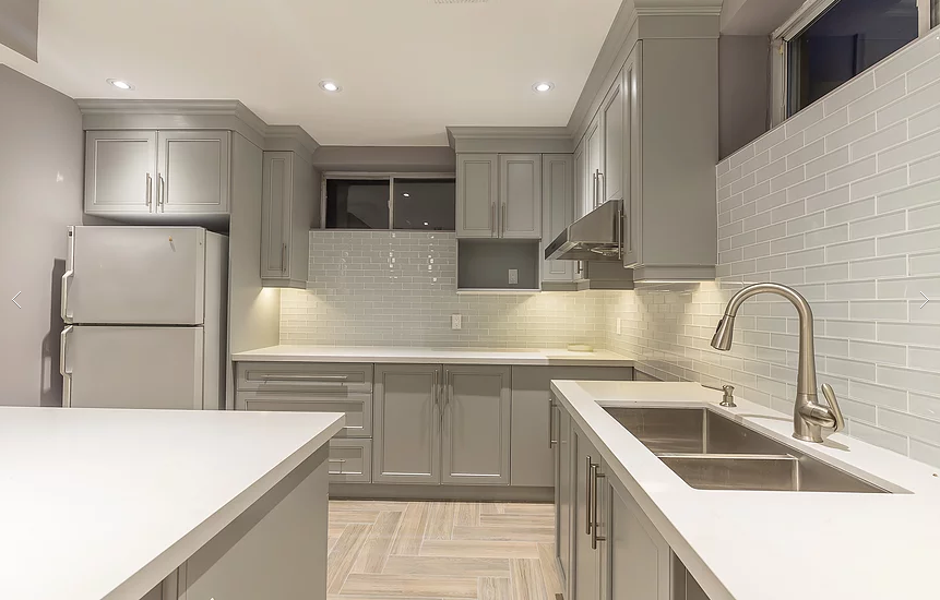 This Toronto basement renovation features a modern custom kitchen with grey shaker cabinets, quartz countertops, a center island, and upgraded lighting. Designed for functionality and style, this basement kitchen includes full cabinetry installation, backsplash tiling, stainless steel appliances, and optimized layout for comfortable living. Completed by a professional Toronto renovation company specializing in basement finishing and interior upgrades.