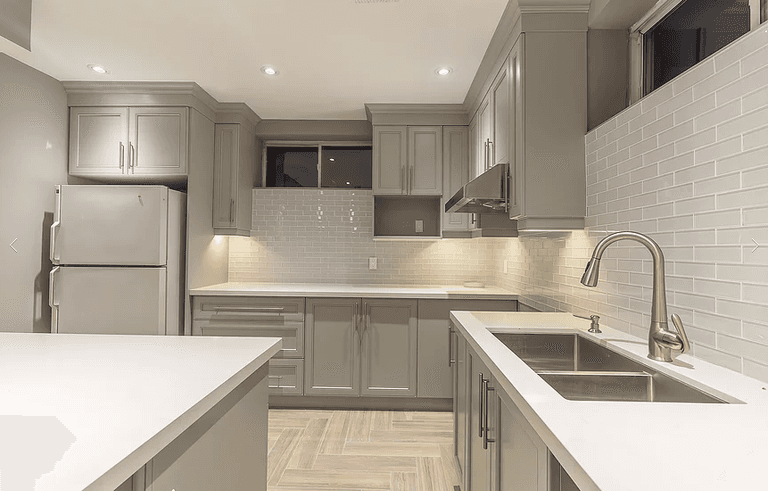 This Toronto basement renovation features a modern custom kitchen with grey shaker cabinets, quartz countertops, a center island, and upgraded lighting. Designed for functionality and style, this basement kitchen includes full cabinetry installation, backsplash tiling, stainless steel appliances, and optimized layout for comfortable living. Completed by a professional Toronto renovation company specializing in basement finishing and interior upgrades.