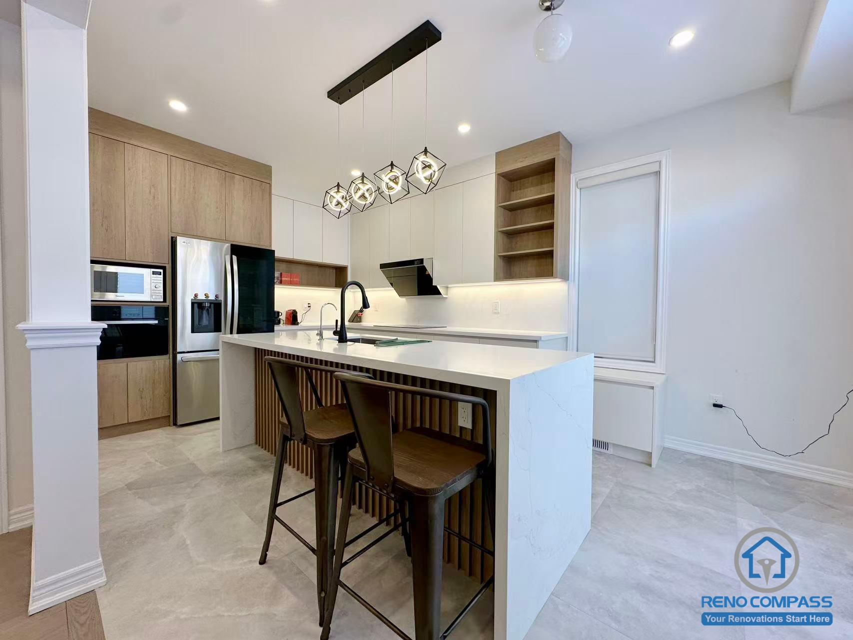 This Stouffville kitchen renovation showcases a contemporary island design featuring vertical wood panel detailing, a quartz countertop, and a matte black sink and faucet. Modern pendant lighting and full-height cabinetry create a bright, open-concept cooking and dining space. Completed by a reliable Toronto renovation company, Reno Compass Inc., this project highlights refined material selection and modern kitchen craftsmanship.