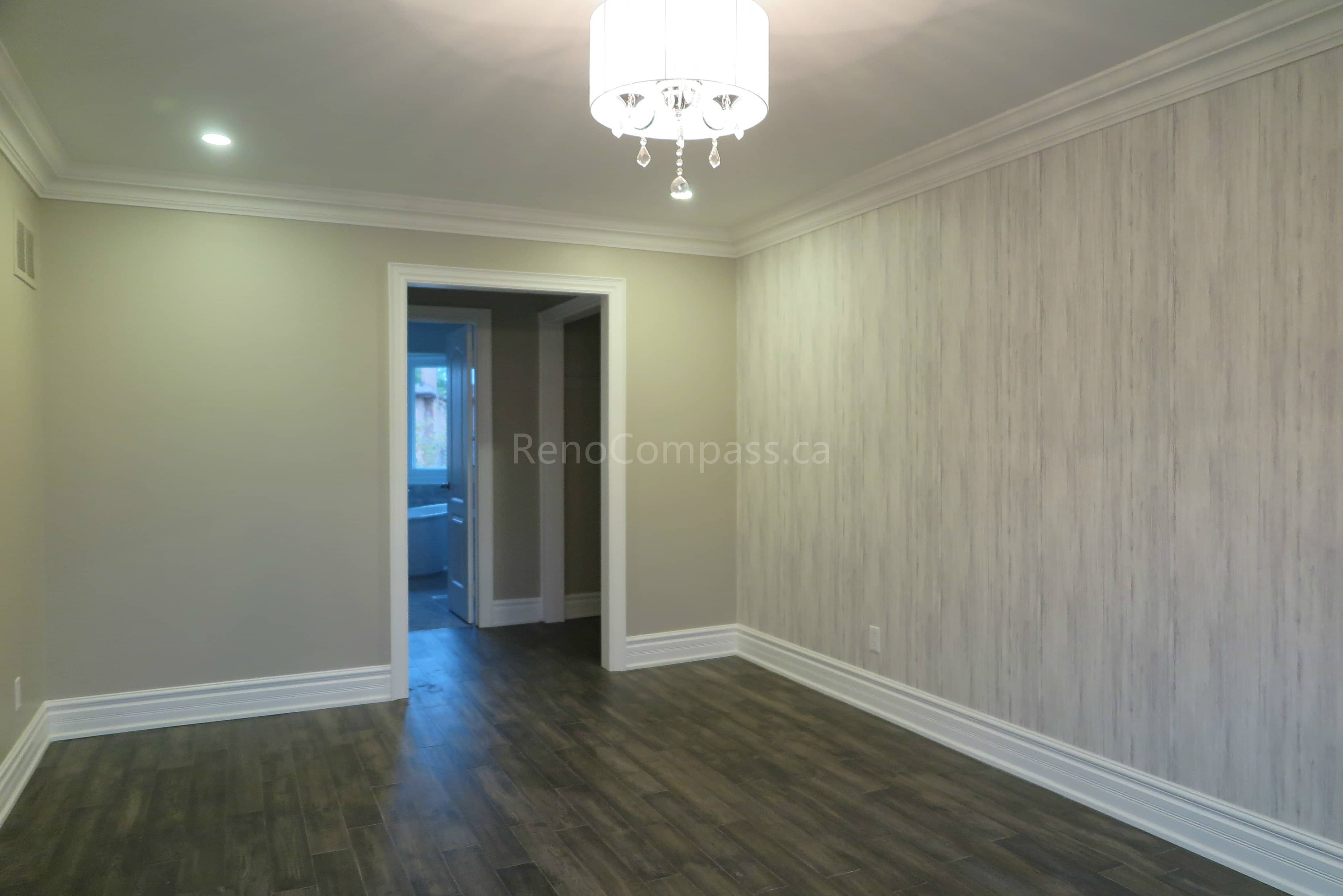 This Markham interior renovation features a refreshed bedroom space with modern hardwood flooring, neutral wall tones, and a stylish textured feature wall that adds warmth and character. Crown molding and updated lighting fixtures enhance the clean and elegant design, creating a comfortable and contemporary living environment. Completed by Reno Compass, a professional renovation contractor specializing in full interior renovations and custom finishing services across Markham and the Greater Toronto Area.