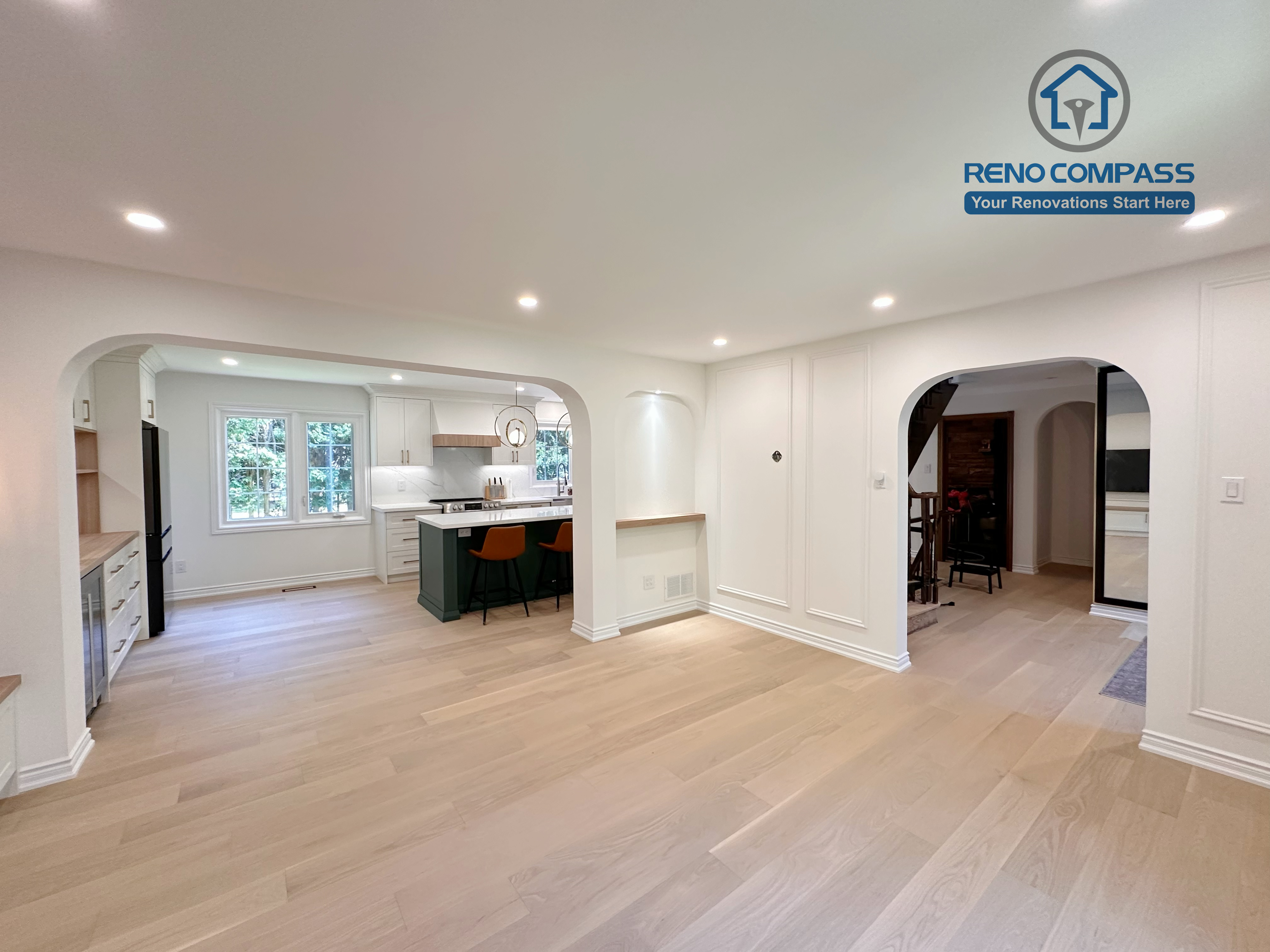 This Markham kitchen renovation showcases an open-plan living area seamlessly connected to the kitchen through elegant arched openings. Wide-plank hardwood flooring, wall panel detailing, and recessed lighting create a bright and cohesive interior. Completed by a professional Toronto renovation company, Reno Compass Inc., the design prioritizes spatial flow, architectural balance, and long-term livability.