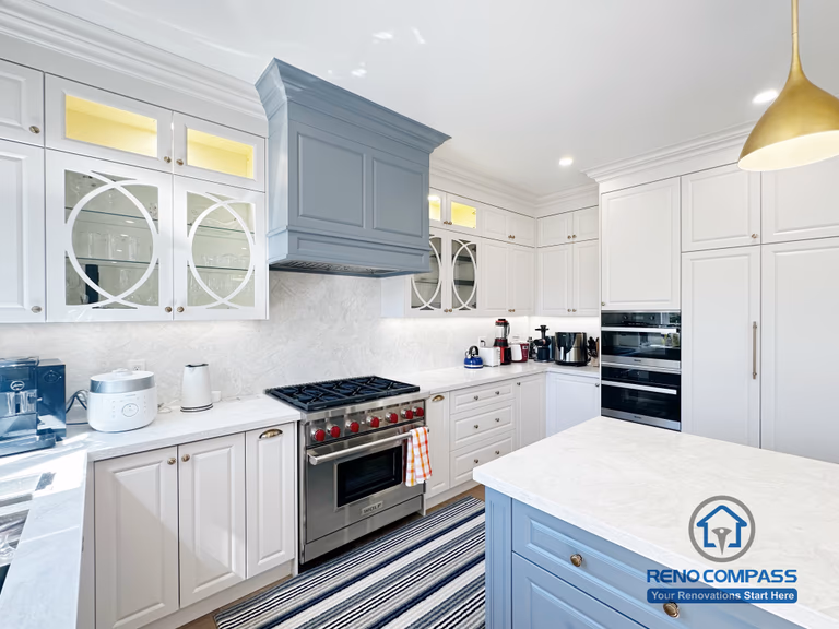 This North York kitchen renovation focuses on the cooking zone, featuring a custom-painted range hood, professional gas stove, quartz backsplash, and detailed shaker cabinetry with glass inserts. Thoughtful lighting and precise cabinetry alignment enhance both functionality and visual balance, reflecting Reno Compass’s attention to detail and craftsmanship.