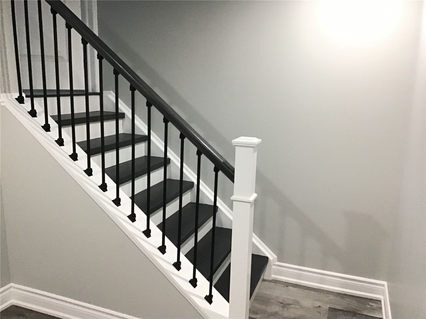 Basement staircase renovation in Newmarket featuring dark stained wood treads, white risers, and sleek black metal railings. This stylish stair upgrade seamlessly connects the main floor to the newly finished basement while enhancing safety and visual appeal.