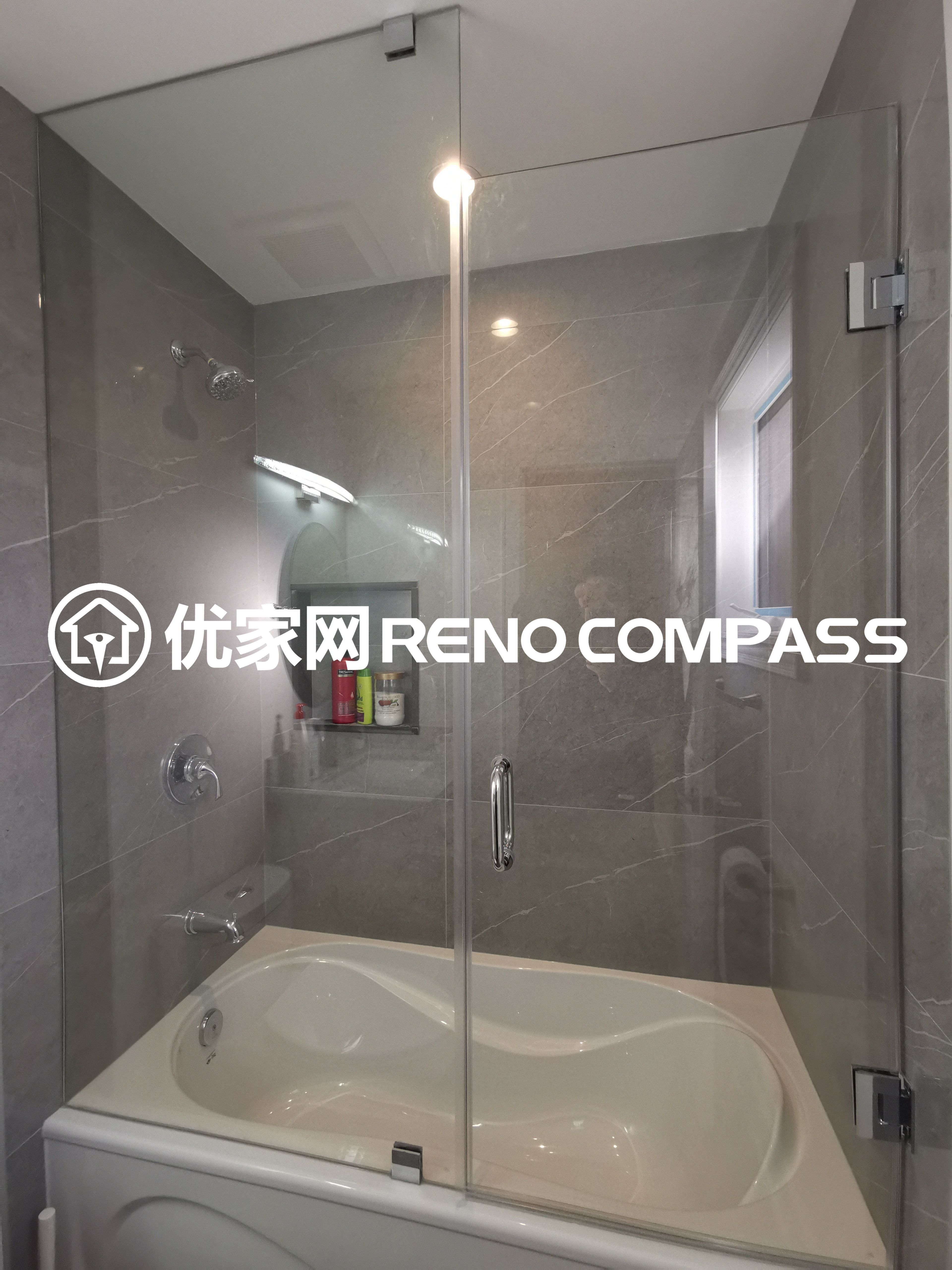 This image showcases a bathtub and shower combination completed as part of a North York interior renovation project. The design features a full glass enclosure paired with large-format wall tiles, creating a clean, modern, and easy-to-maintain bathroom space. Integrated fixtures and a built-in wall niche enhance everyday functionality, while natural light from the window improves brightness and ventilation. The layout reflects careful space planning, durable material selection, and quality craftsmanship suited for contemporary Toronto homes.