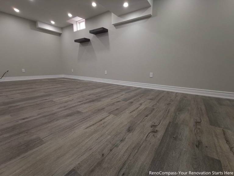 This Oakville basement renovation features a fully finished modern space with upgraded flooring, smooth ceilings, and recessed pot lights that create a bright and comfortable environment. The redesigned basement includes fresh wall finishes, clean trim work, and floating shelves for added functionality and storage. Completed by a professional Toronto renovation company, this basement upgrade enhances usable living space, improves lighting, and adds long-term value to the home while delivering a modern and versatile lower-level living area.