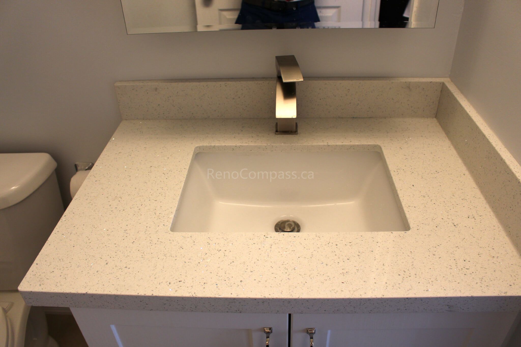 A modern bathroom vanity featuring a sleek rectangular sink, quartz countertop, and contemporary brushed nickel faucet. This elegant Mississauga home renovation by RenoCompass highlights fine craftsmanship and timeless design.