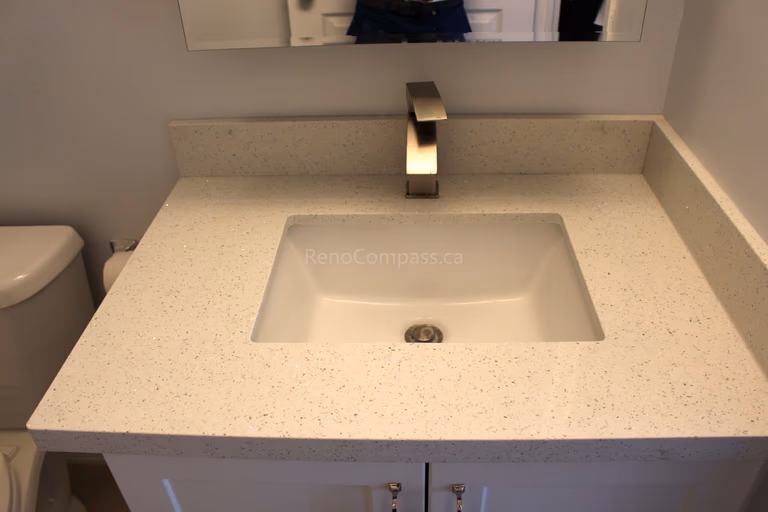 A modern bathroom vanity featuring a sleek rectangular sink, quartz countertop, and contemporary brushed nickel faucet. This elegant Mississauga home renovation by RenoCompass highlights fine craftsmanship and timeless design.