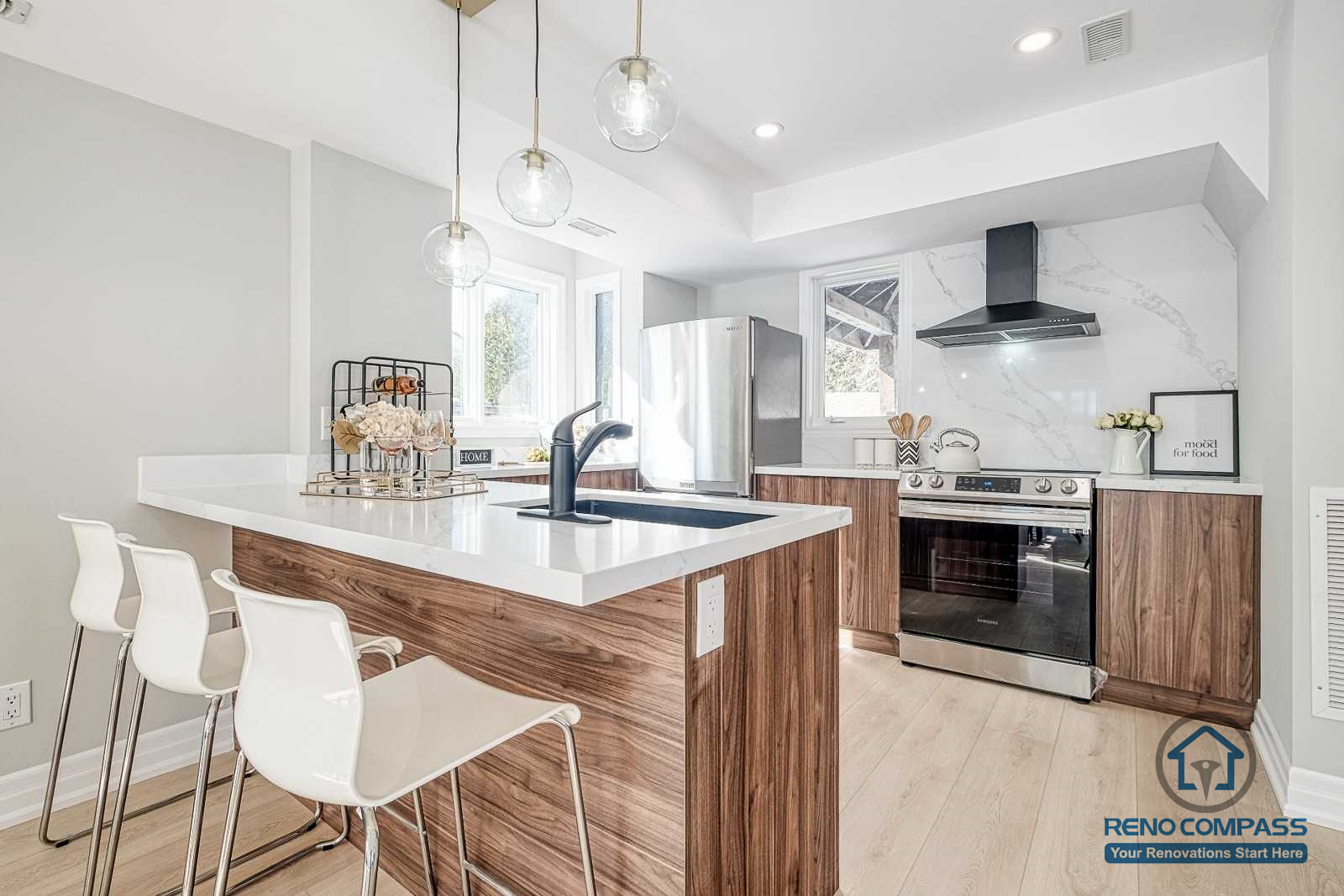 This Georgian interior renovation features a modern kitchen with a spacious island, wood cabinetry, pendant lighting, and clean white surfaces. The layout combines classic proportions with contemporary functionality, completed by a Toronto renovation company.