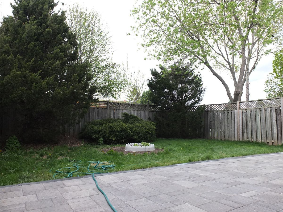 A completed backyard landscaping project in Mississauga featuring a newly installed interlocking stone patio, green lawn area, and decorative garden bed. The grey patio pavers create a clean and durable outdoor space while the surrounding landscaping adds natural balance to the backyard design. Completed by a professional Toronto Renovation Company, Reno Compass Inc., specializing in interlocking patios, landscaping, and exterior home upgrades across the GTA.
