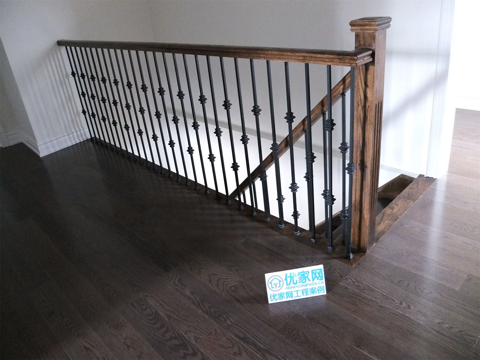Upper-level staircase guardrail installation in a Scarborough home addition project featuring custom wood posts, decorative black iron balusters, and dark hardwood flooring. The renovation enhances safety and adds a modern architectural detail to the newly expanded interior space.