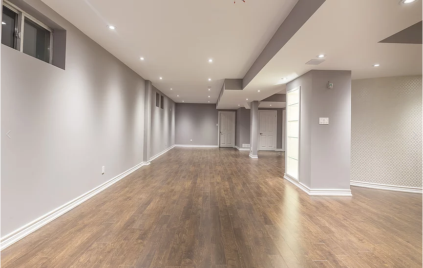 This Toronto basement renovation features a fully finished open-concept basement space with new engineered hardwood flooring, smooth ceilings, and energy-efficient LED pot lights throughout. The neutral wall tones and spacious layout create a bright, modern environment ideal for entertainment, family living, or rental use. Completed by Reno Compass Inc., a professional Toronto renovation company specializing in basement finishing and full interior remodeling.