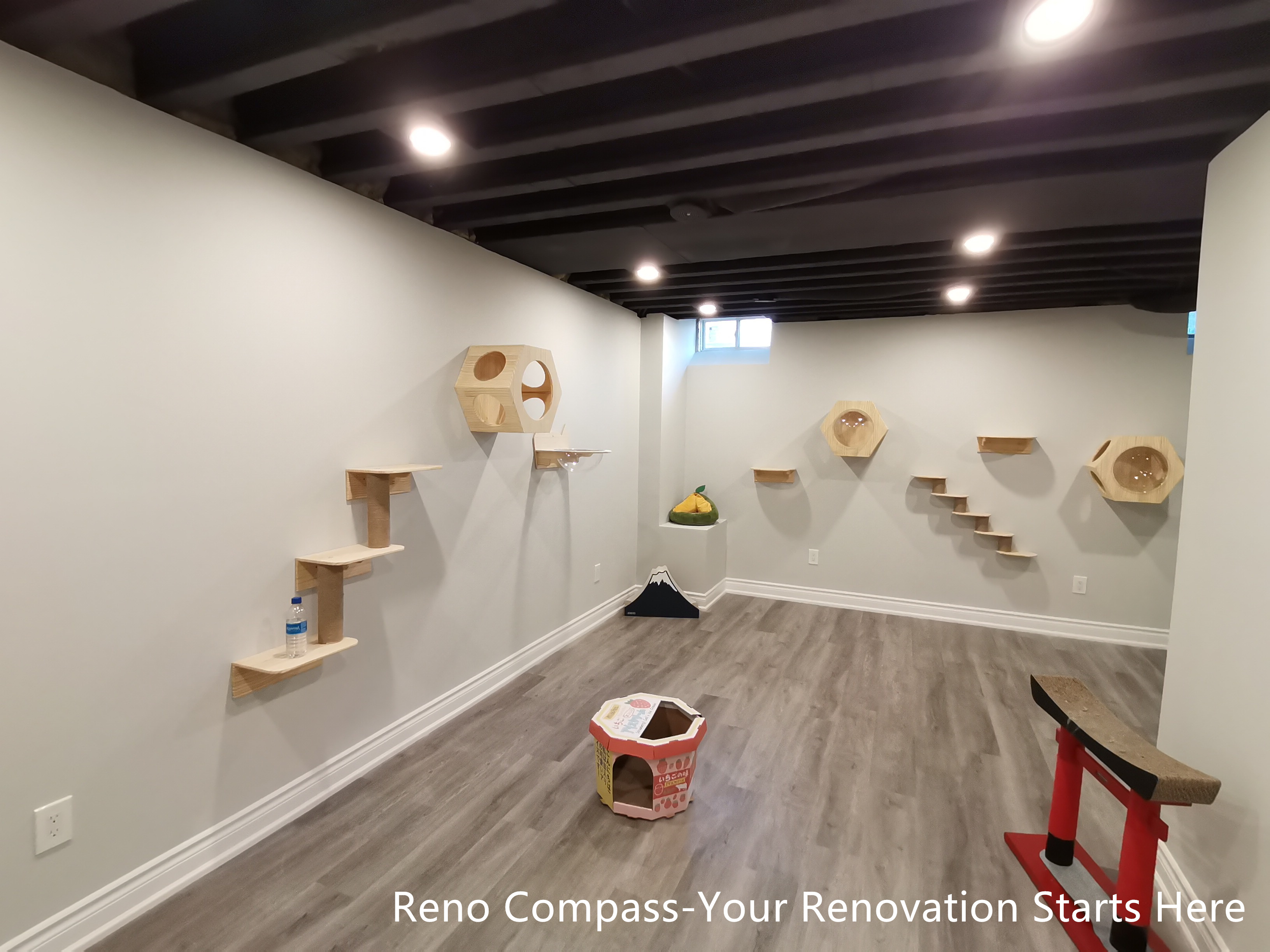 This Vaughan basement renovation features an extended cat climbing wall integrated into an industrial-style interior with a sprayed black open ceiling and recessed lighting. Wall-mounted platforms and climbing elements are arranged along the length of the space, creating a continuous and engaging path for pets while maintaining a clean and organized layout. The durable flooring and neutral wall finishes support everyday use and easy maintenance. Designed and completed by Reno Compass, this renovation highlights thoughtful space planning that balances functionality, movement, and visual clarity in a compact basement environment.