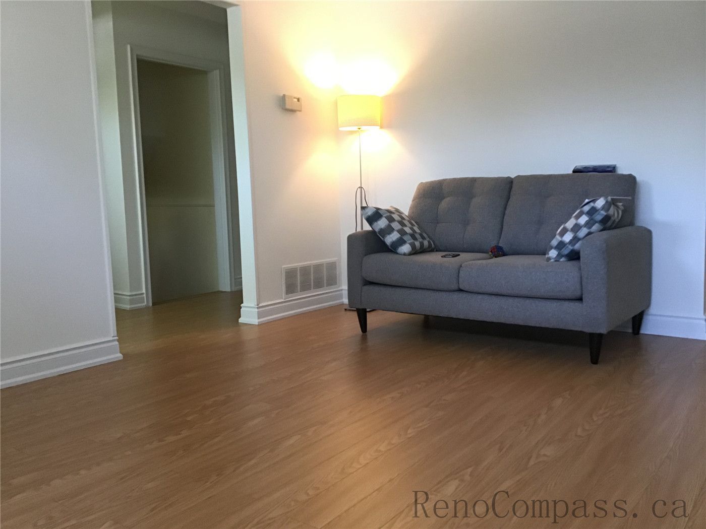 This image features a completed living room flooring renovation in Oakville, showcasing durable hardwood floors paired with a clean and modern interior setup. The warm wood tones complement the neutral furniture and soft lighting, creating a comfortable and inviting residential living space.
