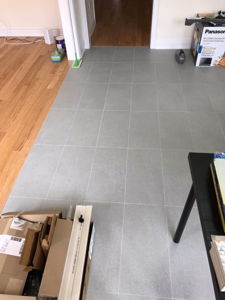 Light grey tile flooring installation in a Toronto interior renovation project. Even tile spacing, clean grout lines, and precise workmanship ensure a seamless transition between living areas, creating a modern, bright, and low-maintenance interior floor finish.