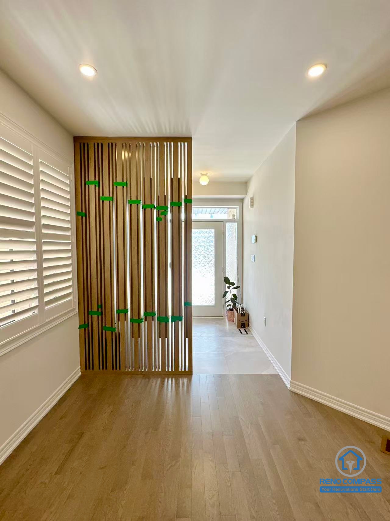 This Stouffville interior renovation highlights a custom wood slat divider used to define the entryway while maintaining an open and airy feel. Natural wood flooring, recessed ceiling lights, and clean wall finishes create a warm yet modern transition space. Designed and built by a professional Toronto renovation company, Reno Compass Inc., this feature demonstrates thoughtful space planning and contemporary interior detailing.