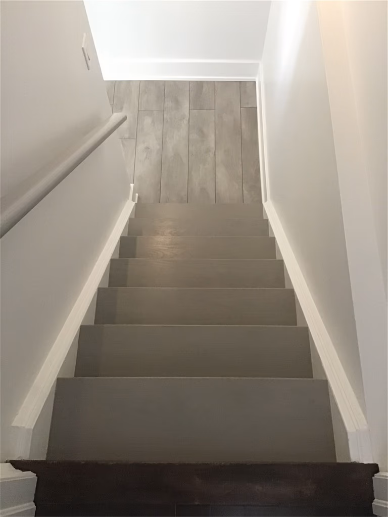 This Markham full home renovation features a clean and modern staircase with updated steps, smooth white railings, and a seamless transition to durable vinyl plank flooring. The neutral color palette enhances brightness and continuity between levels, creating a cohesive and functional layout. Completed by a professional Toronto Renovation Company, this design emphasizes both safety and modern simplicity.
