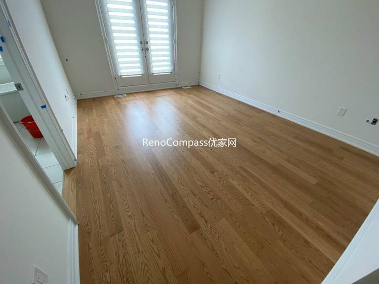 Spacious living area renovation in Richmond Hill highlighting warm wood laminate flooring, crisp wall finishes, and refined trim details. Reno Compass designed this renovation for style, comfort, and durability.