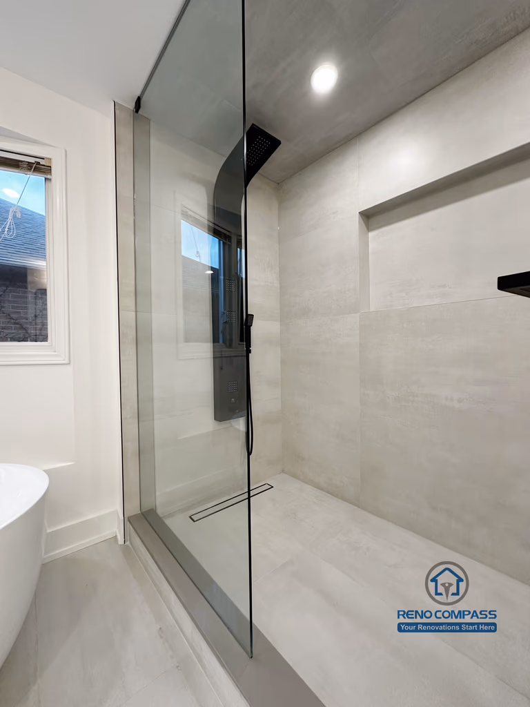 Oakville bathroom renovation featuring a frameless glass shower enclosure, linear floor drain, built-in wall niche, and modern tile finishes, completed by a professional Toronto renovation company.