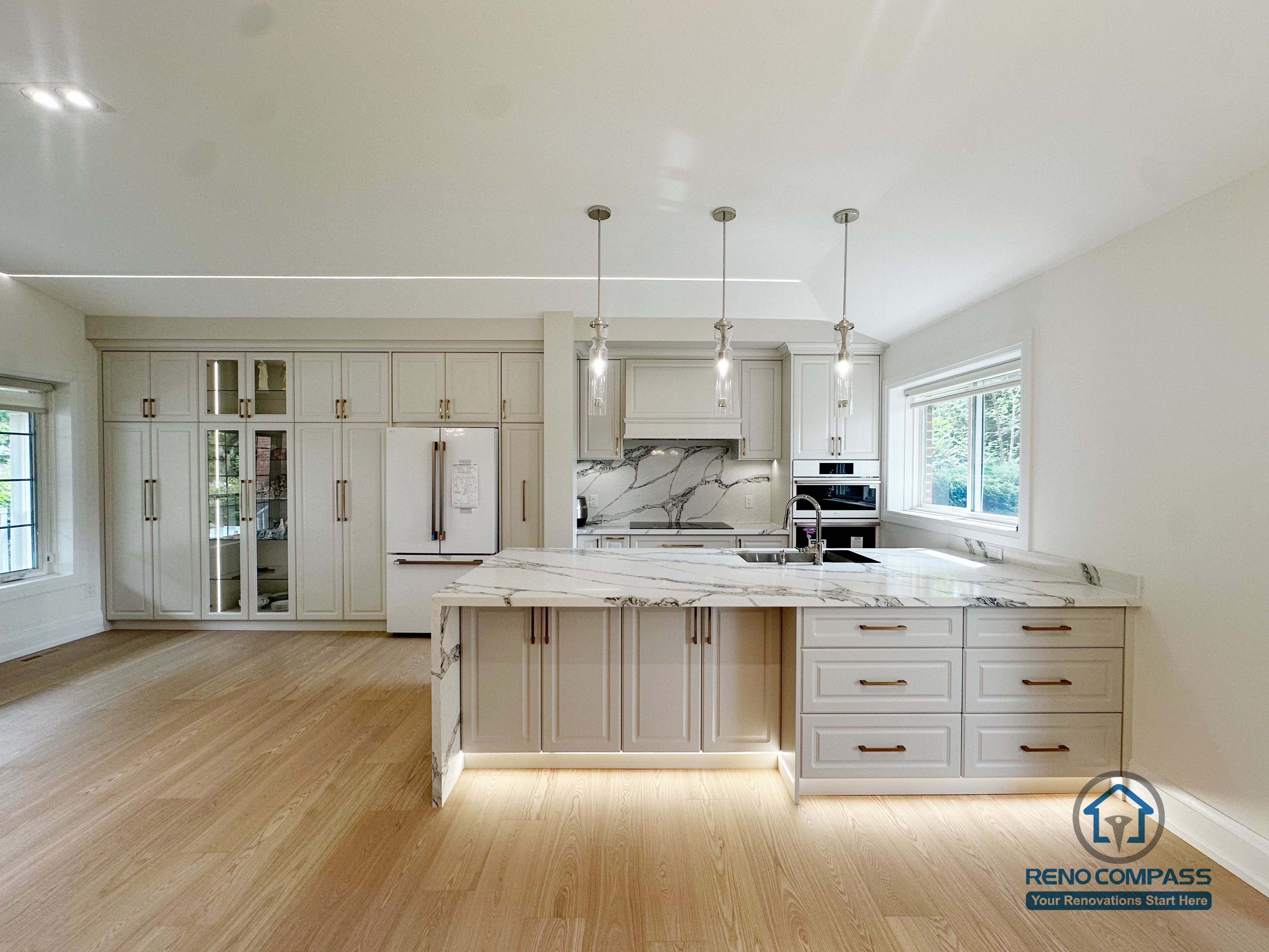 This open-concept kitchen showcases a stunning waterfall island, floor-to-ceiling cabinetry, and soft under-cabinet lighting. The balanced mix of marble textures and warm wood tones creates an inviting, high-end cooking and entertainment space.
这套厨房采用整面落地收纳柜、瀑布式中岛台面以及柔和的灯光设计。大面积浅木地板搭配大理石纹路，让空间既通透又有质感，是功能与美感兼具的轻奢厨房范本。