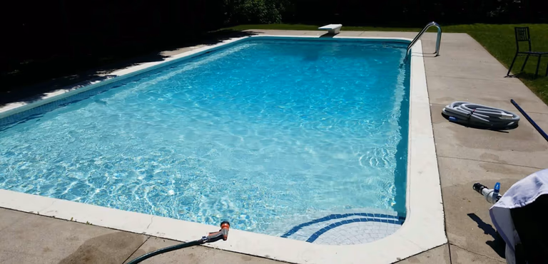 After renovation photo of a fully restored backyard swimming pool in Toronto. The new bright blue liner, clean water, and resurfaced edges highlight the professional pool transformation from old and damaged to modern and inviting. Expert pool renovation by local Toronto specialists.